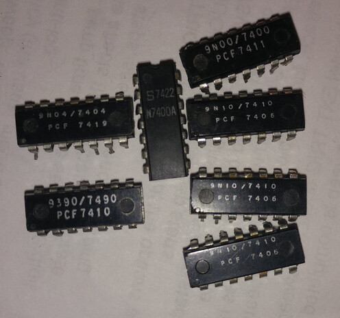 7 14 pin black chips on a white background. They are all 74xx series, produced in 1974 and thus with a date code of 74xx