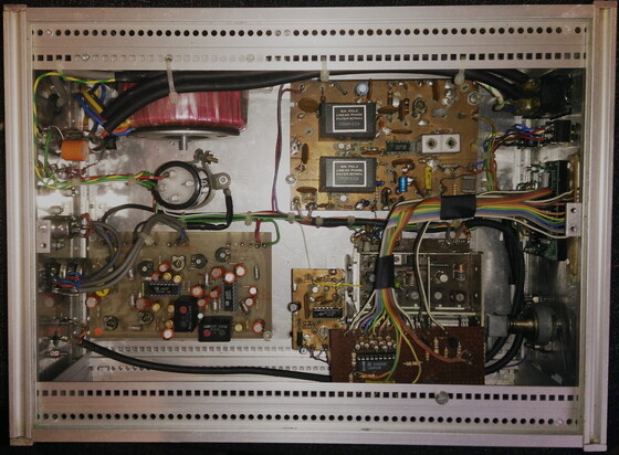 Inside of a home built FM radio receiver. Nice fat torroidal Power transformer, ~4 circuit boards of various sizes and a variety of cables; including a rainbow ribbon going to a bargraph on the front.
