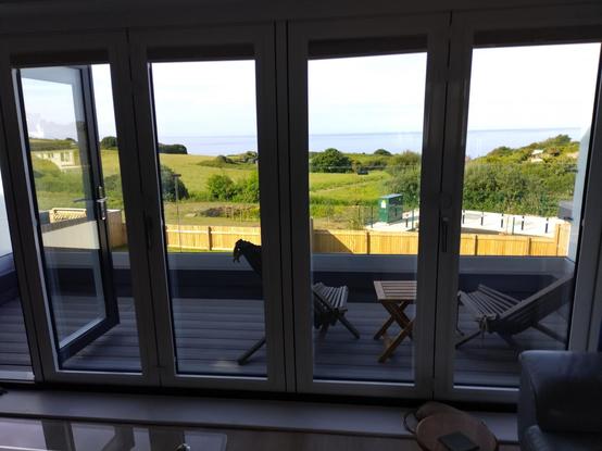 View out of a window over some fields to the sea near The Mumbles in the distance