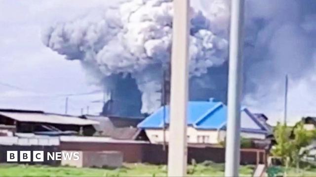 footage of the aftermath of a drone attack on an airfield. Smoke billows in the distance.