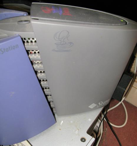 The side of a JavaStation Krups, it's shape is ...odd.  Quite smooth, ovalish in cross section, on the side is a Java logo, and there's another on the top, It's mostly grey with two wings at the back in Purple and some cooling vents inbetween.