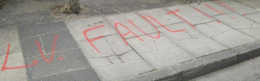 The words 'L.V. Fault!!!' sprayed in red on the (very broken) pavement.