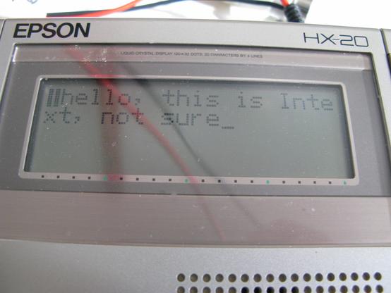 The small LCD screen of an EPSON HX20 saying 'hello, this is Intext, not sure'