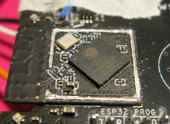 An ESP32-S3-mini module on a PCB with it's top removed showing the chip and oscillator and a few passives inside