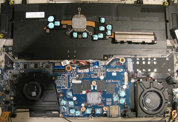 The inside of a laptop;  normal stuff, battery, fans, ram etc - and the heatsink is off and sitting on top of the battery; it's got some minty green blobs of thermal paste on.