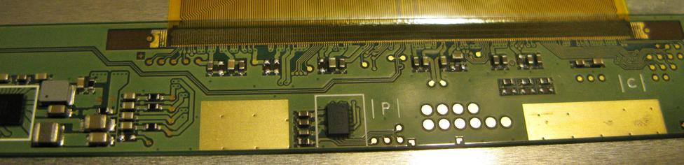 One part of the board of the LCD showing another chip, passives and a damn fine pitch ribbon to the PCB, and some test points.