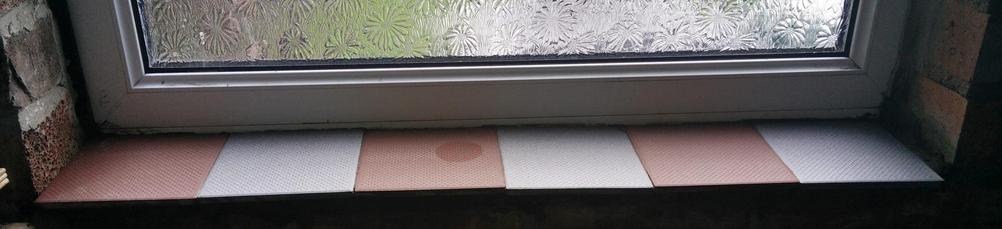 A window ledge; the sides are raw brick, the ledge itself is 6 tiles in alternating red and grey.