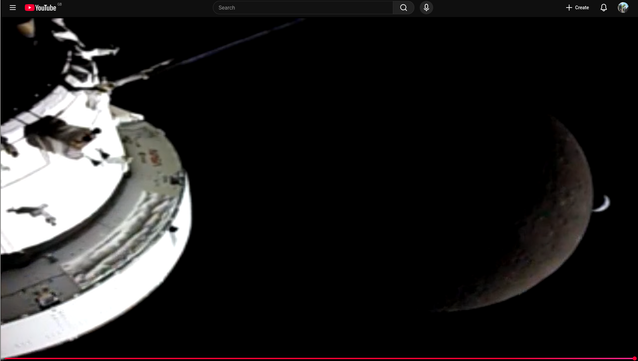The Orion space craft, facing a dark moon and a crescent earth in the background as it goes into eclipse behind it.