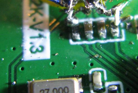 A close zoom on a PCB showing 4 SMT components, with 2 white wires bodged onto them.