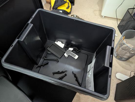 A black 45L plastic box with a smattering of failed prints and old prototypes in the base.