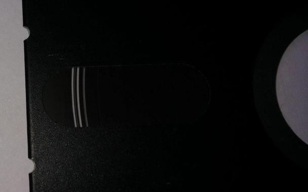 A zoom of a 5¼" floppy with some transparent bits on the surface where the oxide came off.