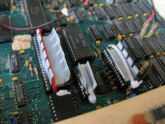 A BBC B motherboard showing various chips; on top of the CPU, the 74LS245 and Video ULA are bodged heatsinks held on by a wiretie, some glue and a dab of compound.