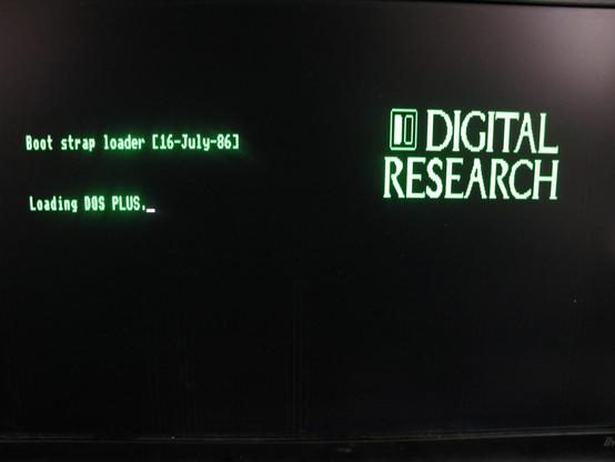 A green 'Digital Research' loading page 'Boot strap loader [16-July-86]   Loading DOS PLUS.' With a nice blur that is probably camera rather than a CRT!